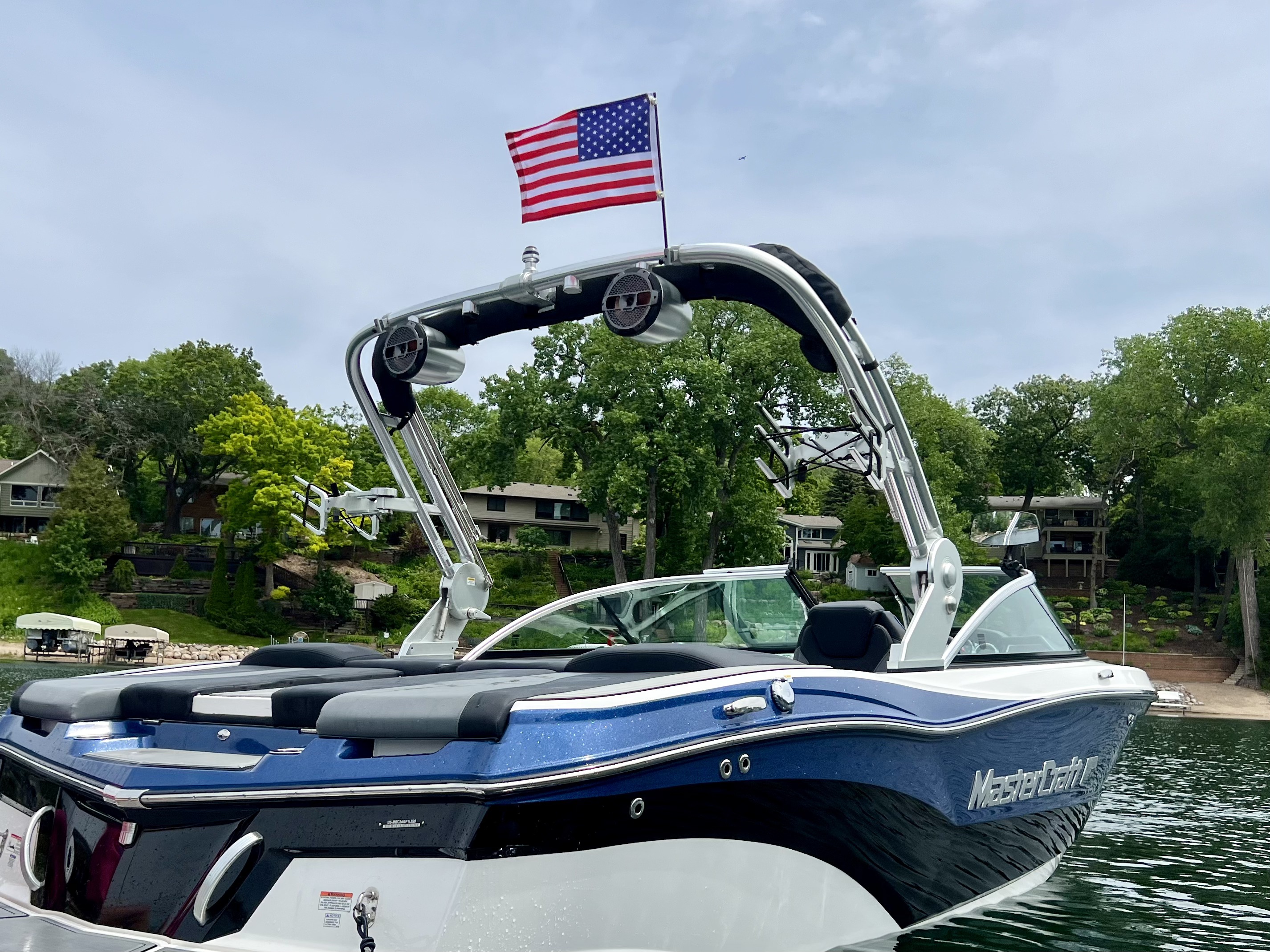 Blue MasterCraft boat with an American flag flying above its tower